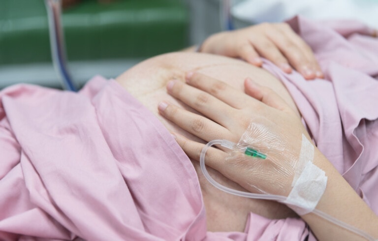 Close up of pregnant woman with IV solution in delivery room
