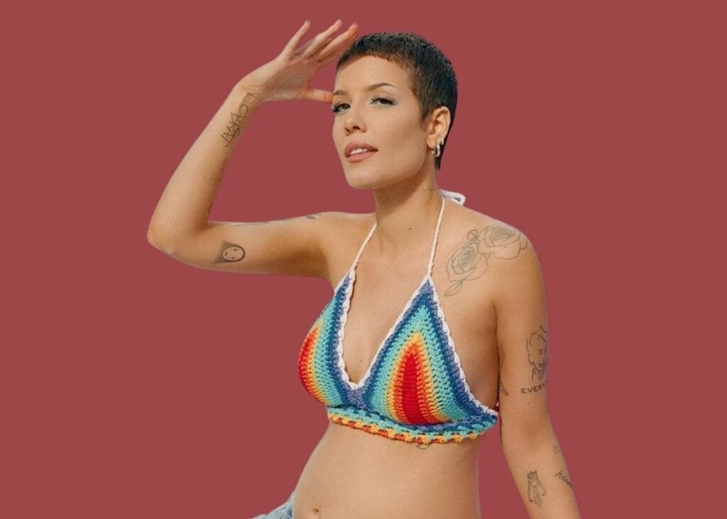 Pregnant Halsey posing for the camera in a rainbow bikini top.