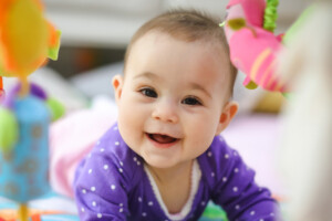 Happy baby girl doing tummy time on a play mat.