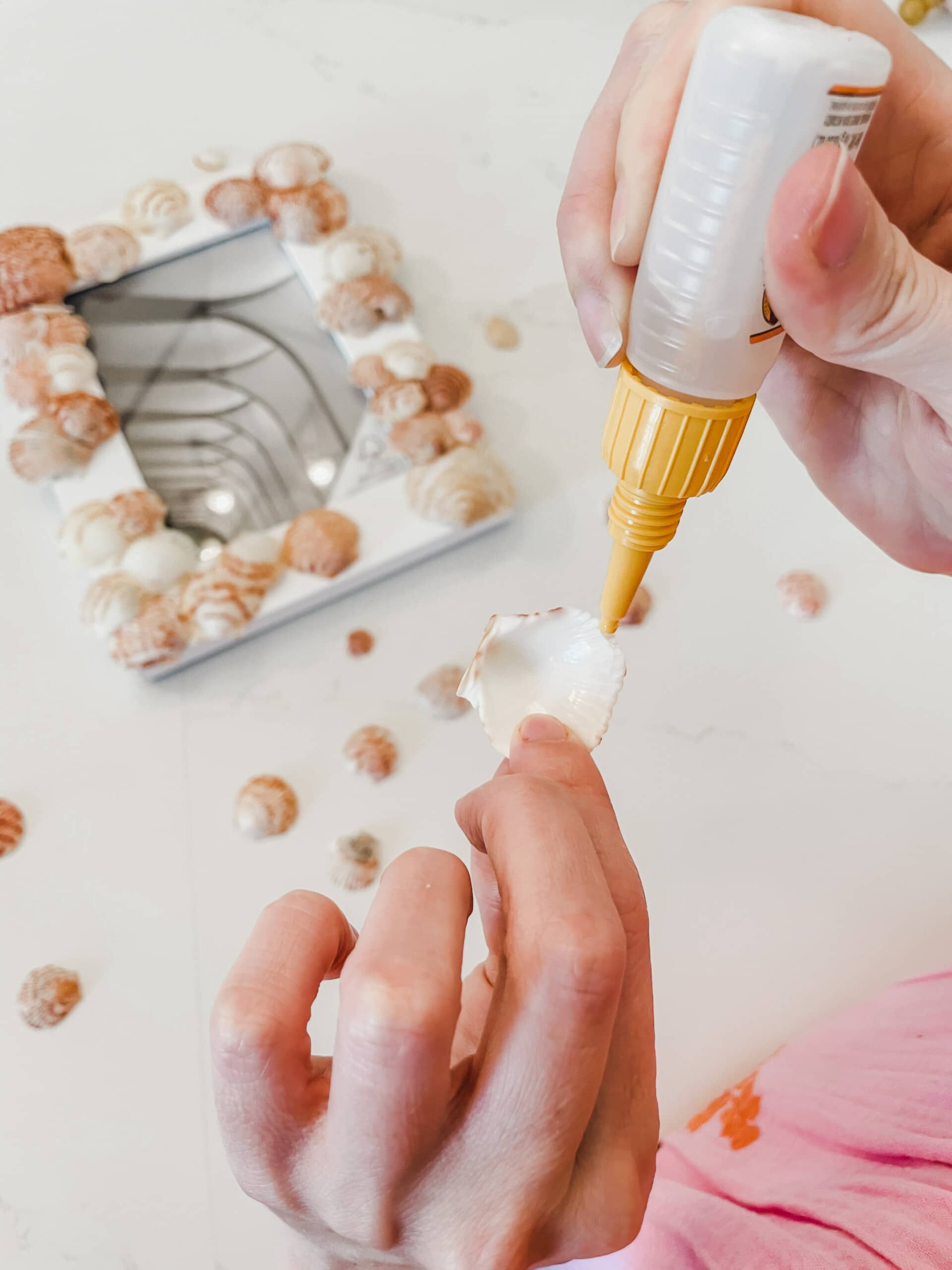 Woman's hands adding glue on edges of a seashell.