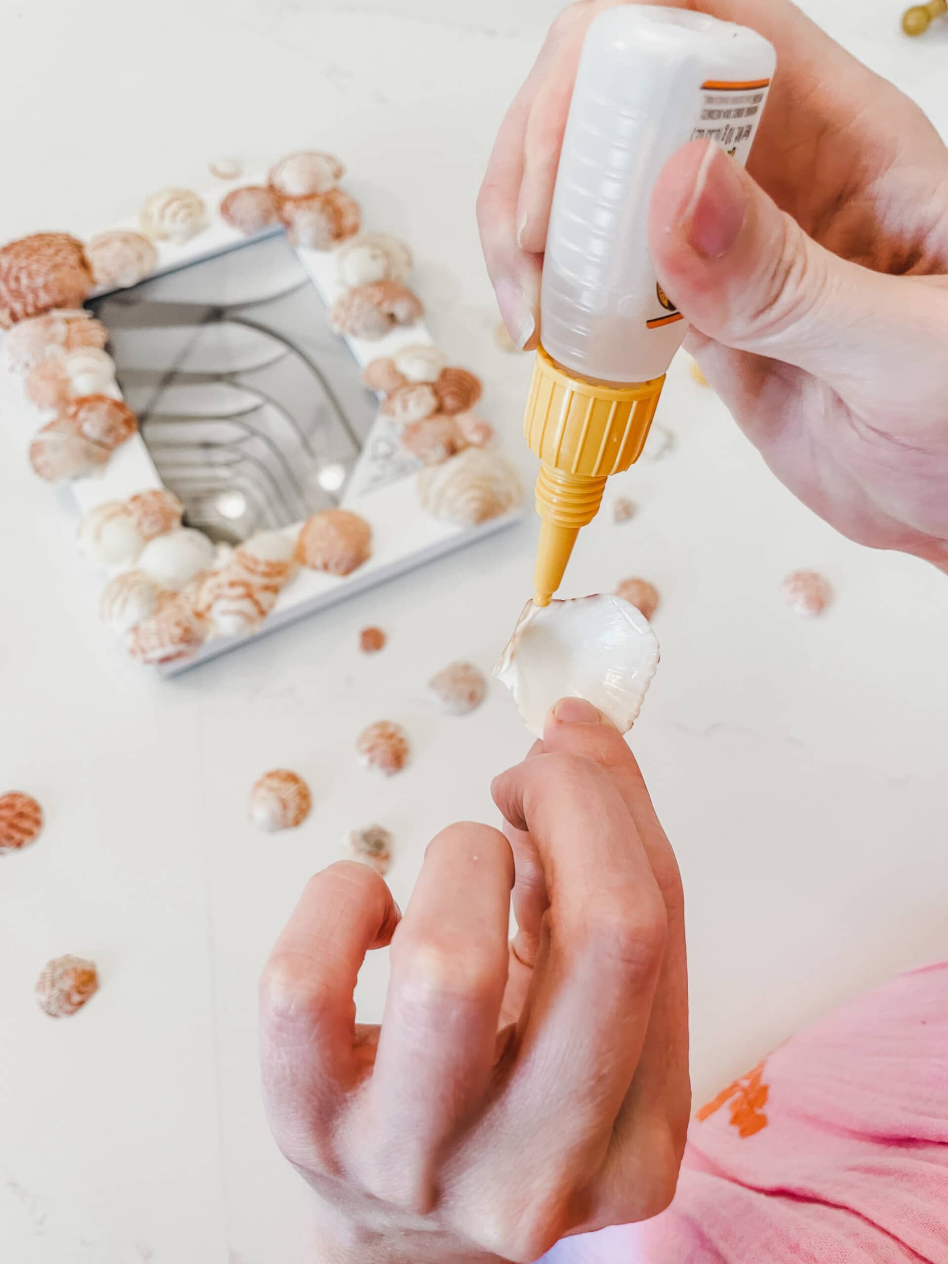Woman's hands adding glue on edges of a seashell.