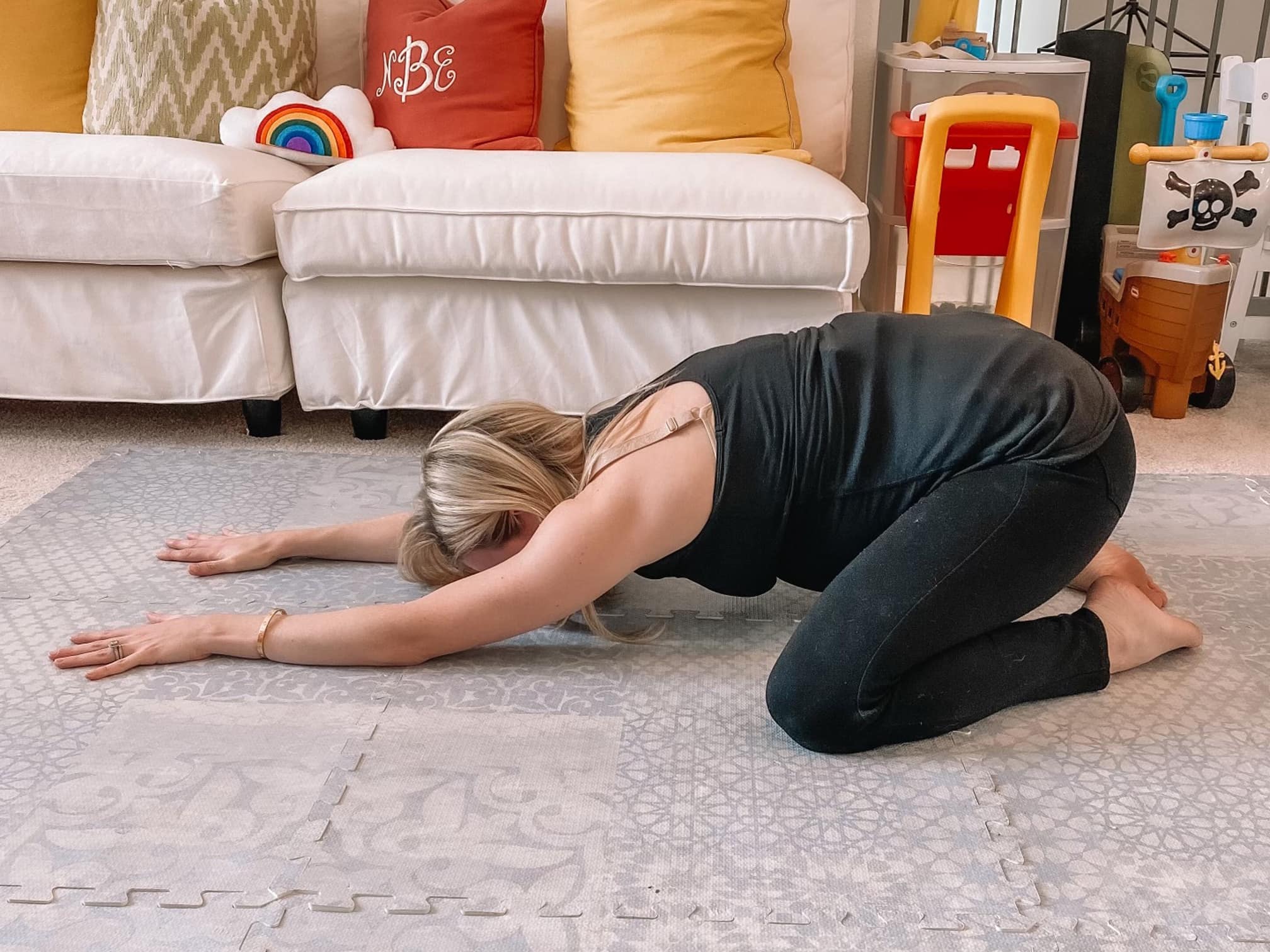 Pregnant woman doing a child's pose yoga stretch.