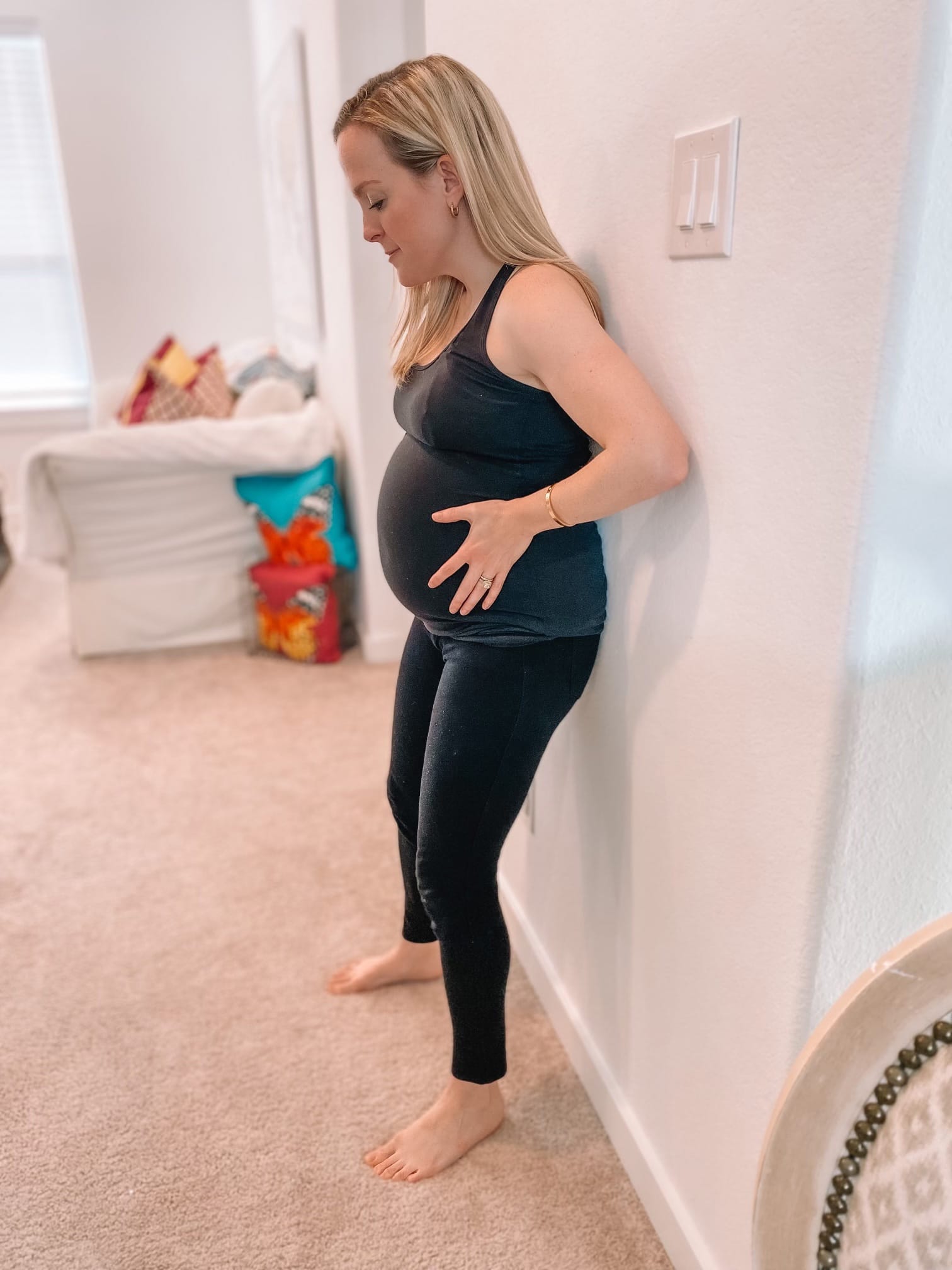 Pregnant woman doing a pelvic tilt against the wall.