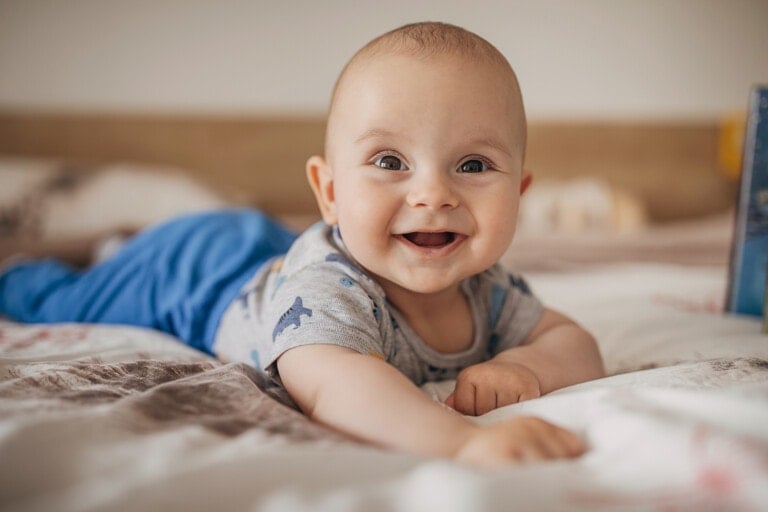One boy, beautiful baby boy lying on bed and smiling.