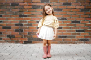 Cute little girl dressed up and posing in front of a brick wall.
