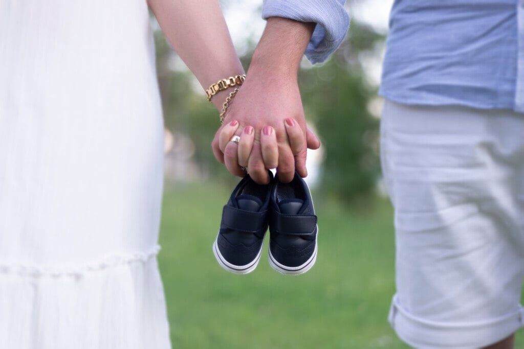 Midsection view of young parent candidates holding a pair of unborn baby's little shoes.