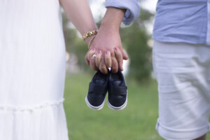 Midsection view of young parent candidates holding a pair of unborn baby's little shoes.