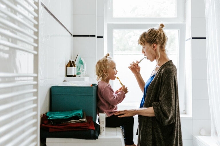 Young mother with a child brushing their teeth in the bathroom.