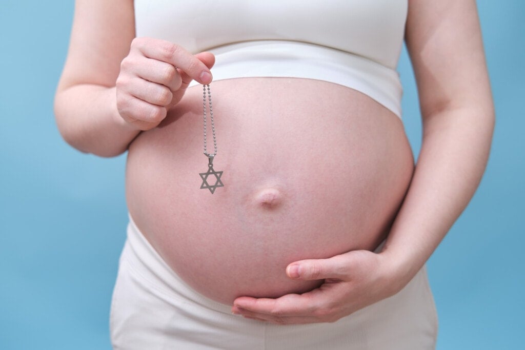 A symbol of the Jewish religion in the hands of a pregnant woman, a studio photo on a blue background