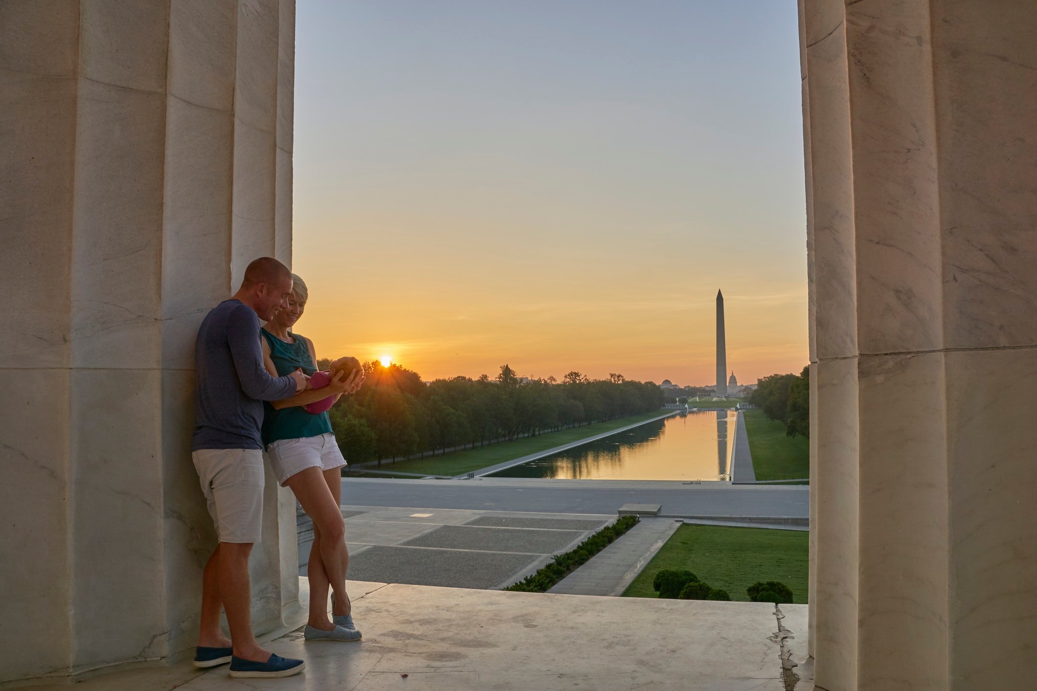 Couple with a Baby at the Lincoln Memorial with the Washington Memorial in the Background at Sunrise in Washington DC Capital of the USA