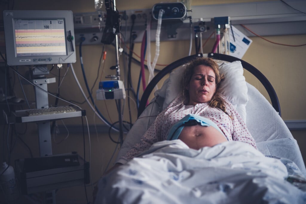 Young pregnant mother is preparing to have her first baby. She's sitting in the hospital bed breathing through a contraction.