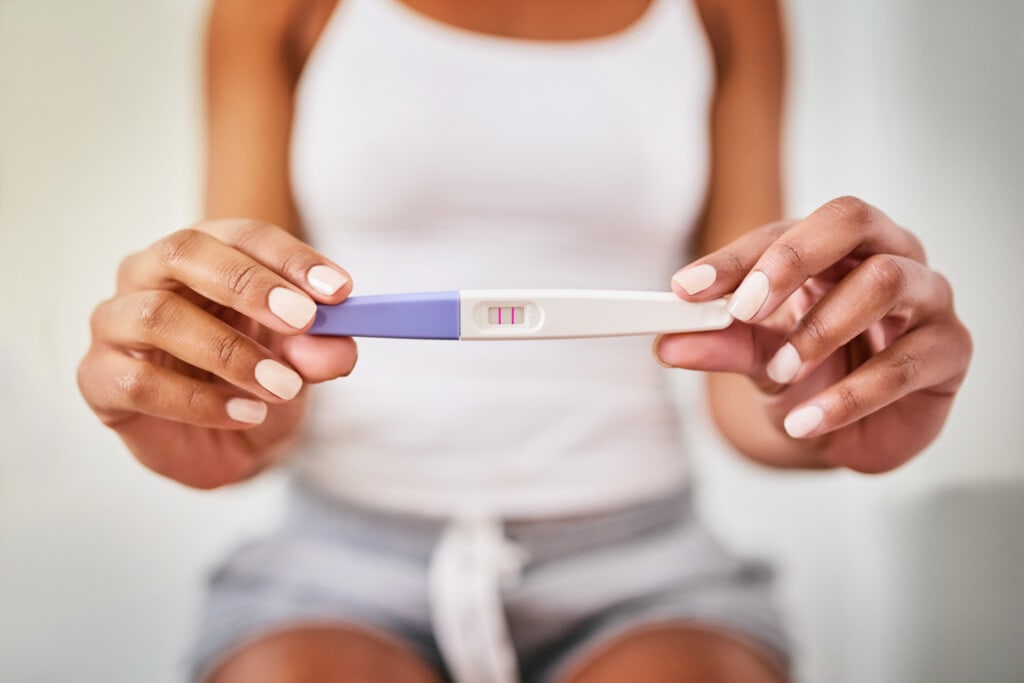 Cropped shot of a woman taking a pregnancy test while sitting on the toilet