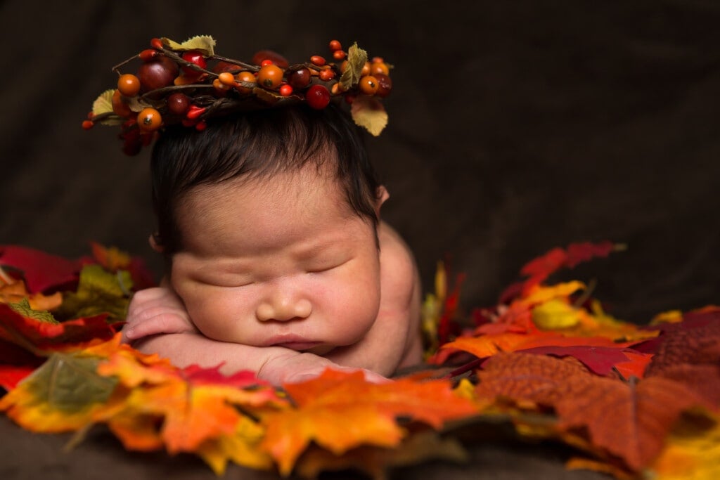 6 days old baby girl sleeping in fall leaves and cranberry flower crown