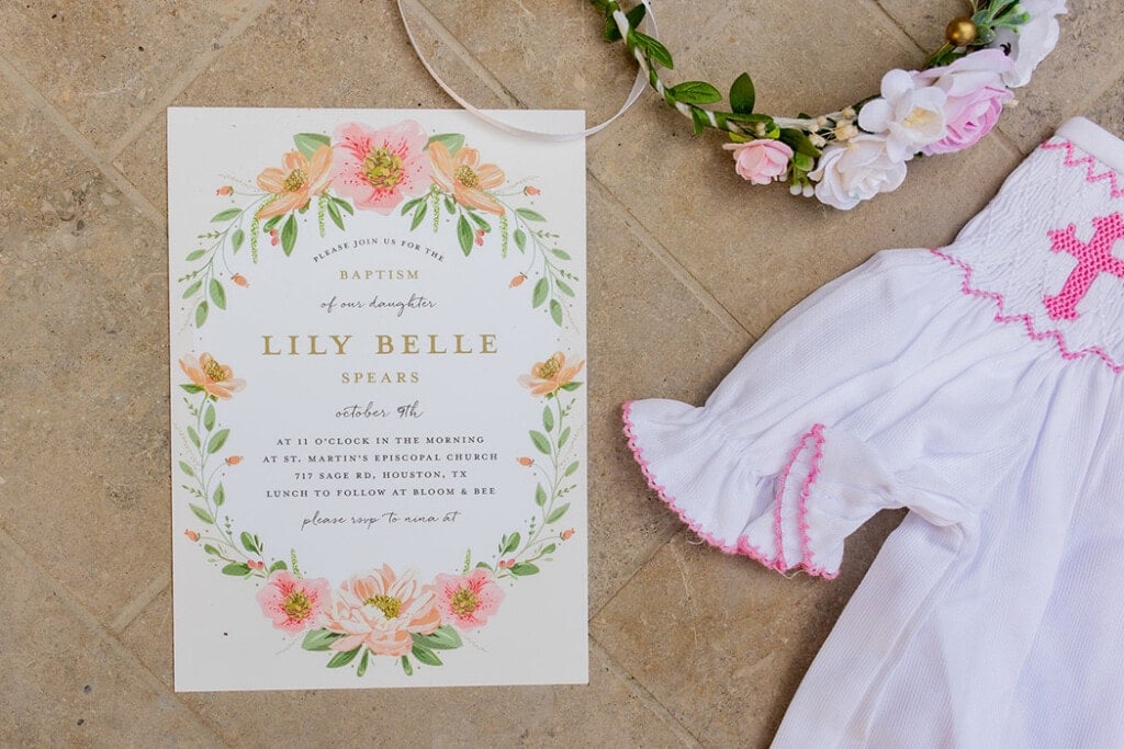 Baptism invitation laying on the ground with a flower crown and dress.