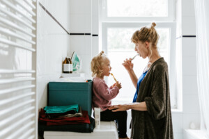 Photo of a young mother with a child brushing their teeth in the bathroom at home. Shot in Berlin.