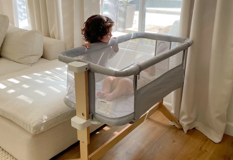 Toddler looking at baby in bassinet