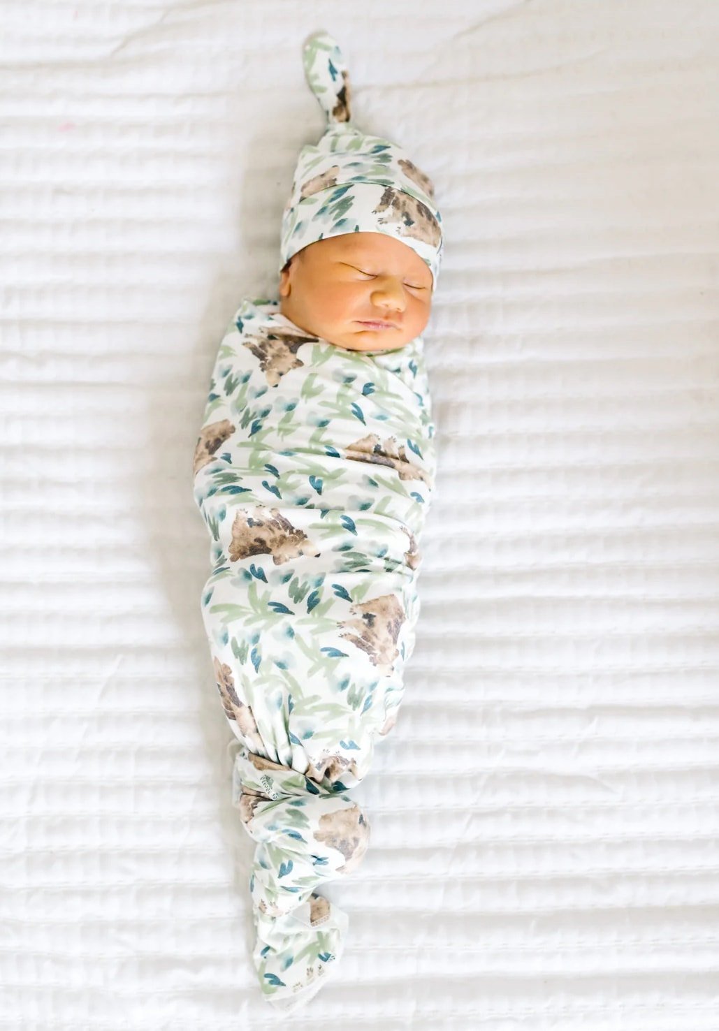 Baby in floral print swaddle with matching hat