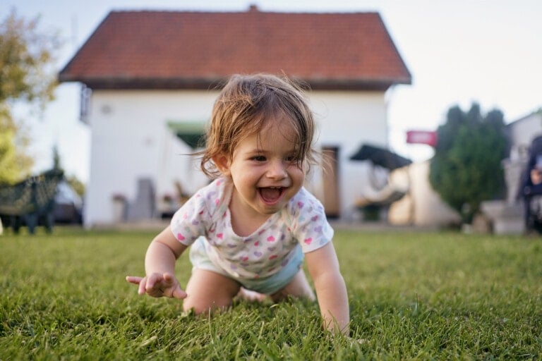 Beautiful innocent baby girl having fun playing in the back yard in summer on a sunny day.
