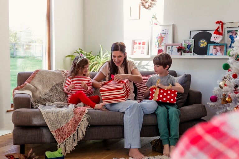 Children in living room with their mother to open their Christmas presents