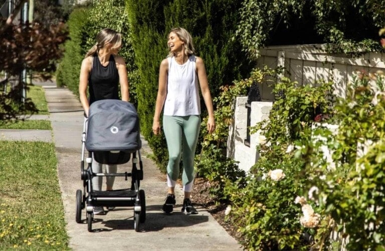 Kath Baquie walking with a new mom who is pushing a stroller.
