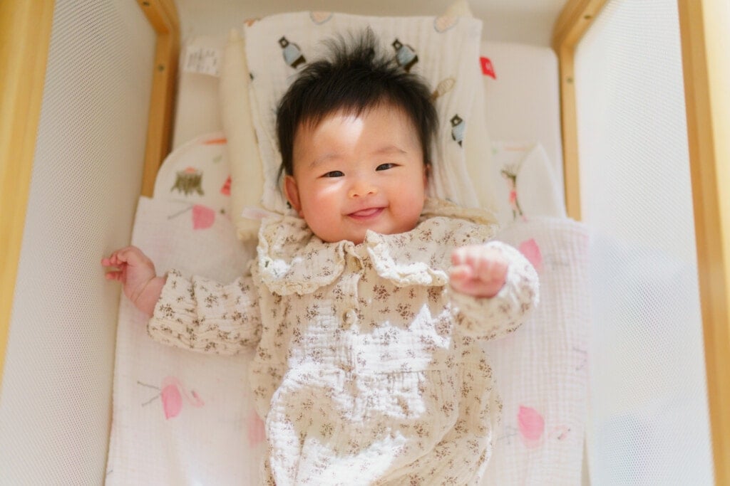 A portrait of a small baby looking at the camera and smiling.