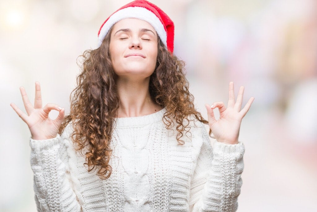 Young brunette girl wearing christmas hat over isolated background relax and smiling with eyes closed doing meditation gesture with fingers.