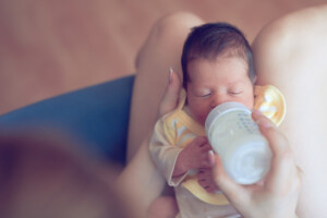 lifestyle shot of newborn baby girl eating milk from milk bottle.