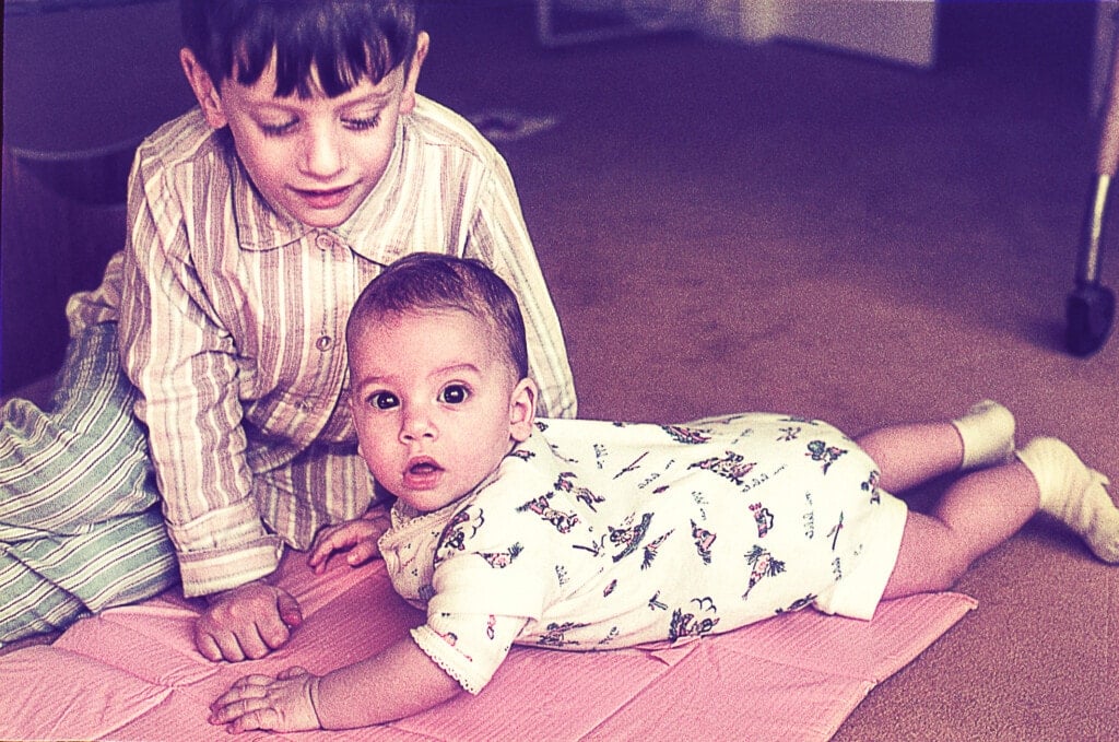 Vintage photo of a boy with her baby sister on the floor at home.