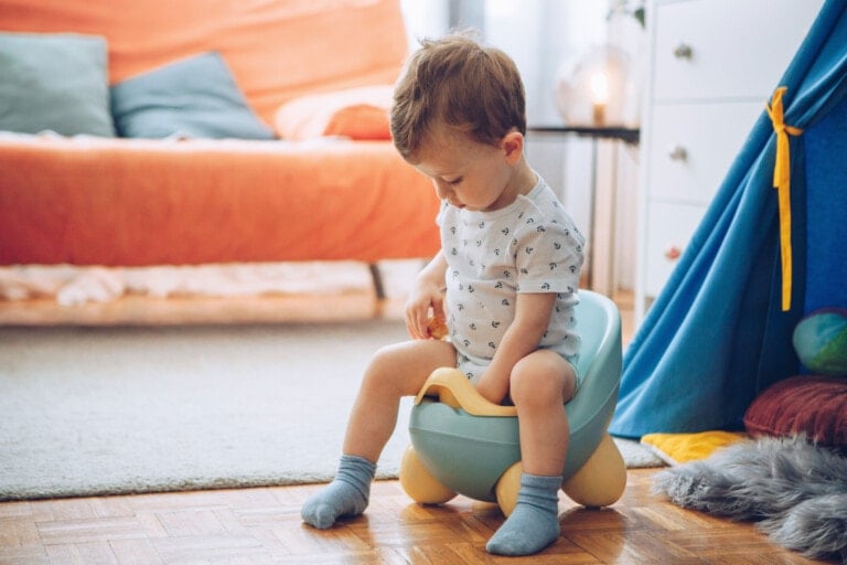 Baby boy in socks sitting on potty.