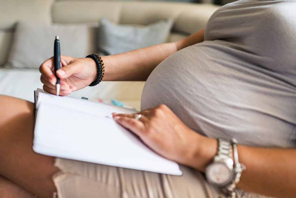 Close-up of a pregnant woman making to do list.