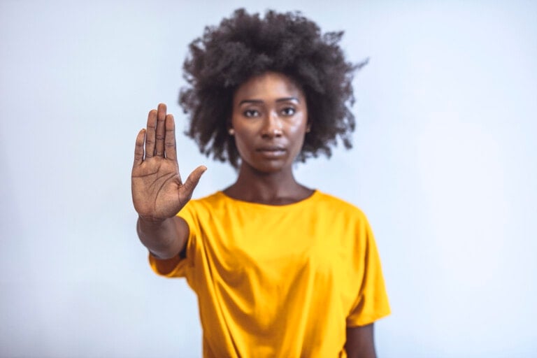 Photo of African american young woman making stop gesture with palm of her hand on grey background