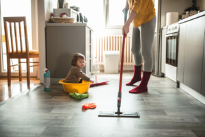 Young mother with a baby girl doing housework