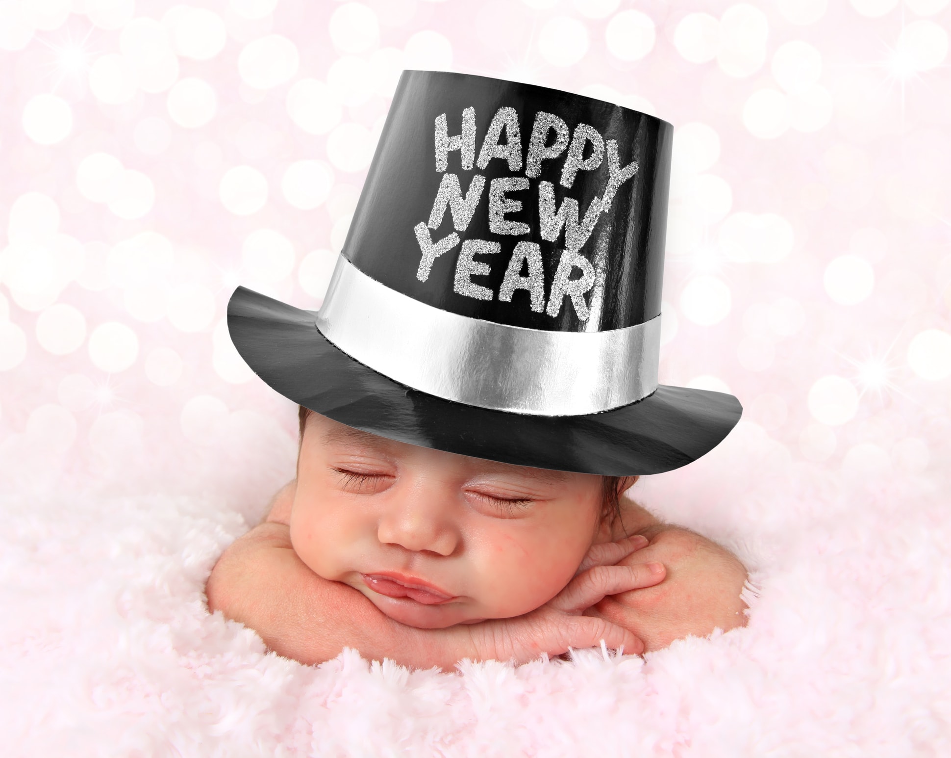 Newborn baby girl wearing a Happy New Year hat.