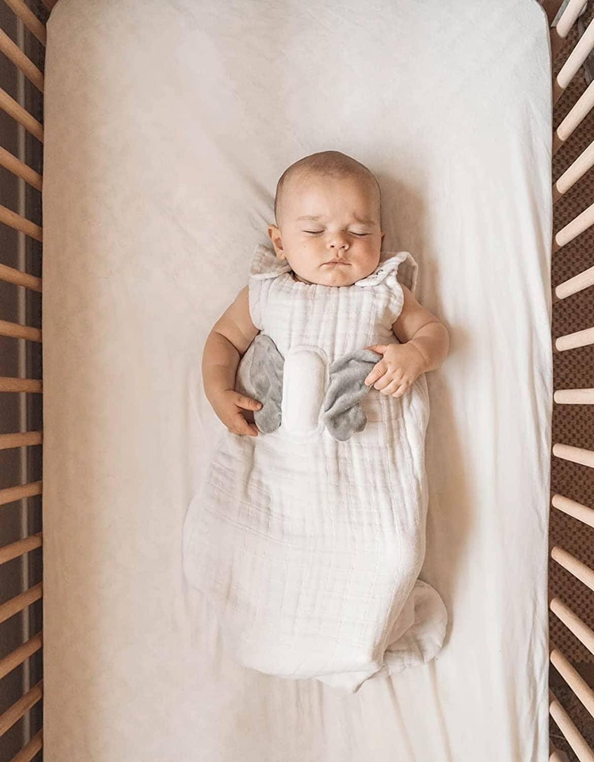 A baby sleeping in his crib wearing a Snuggy Buddy sleep sack.