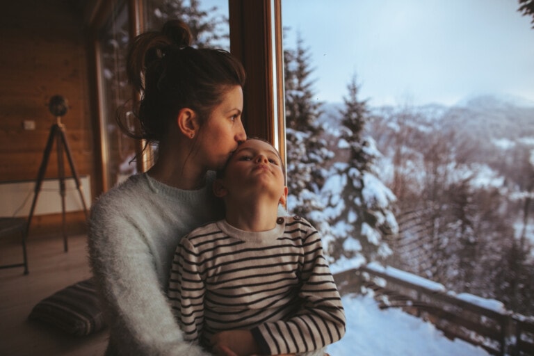 Photo of young mother bonding with her son in a log cabin during winter holidays