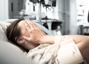 Young woman patient lying at hospital bed feeling sad and depressed worried.