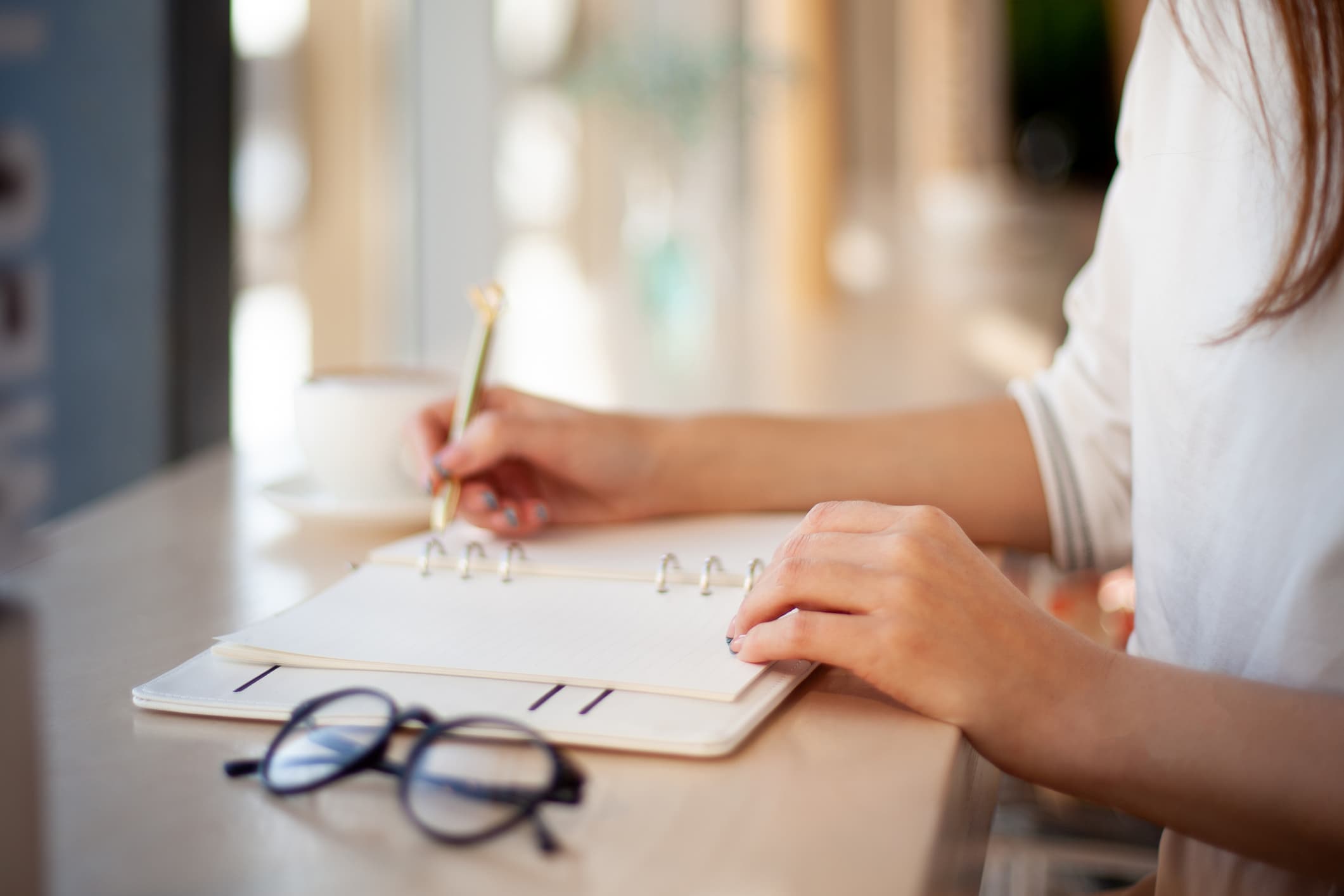 Young businesswoman in eyeglasses planning and writing down the daily schedule in agenda. Time management and calendar reminder event for planner concept. Planning appointment and meetings.