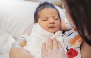 Closeup portrait of young asian Indian mother holding newborn baby with copy space.