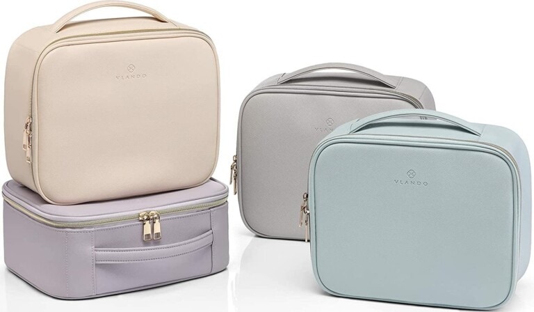 Four travel makeup cases in cream, purple, blue, and grey