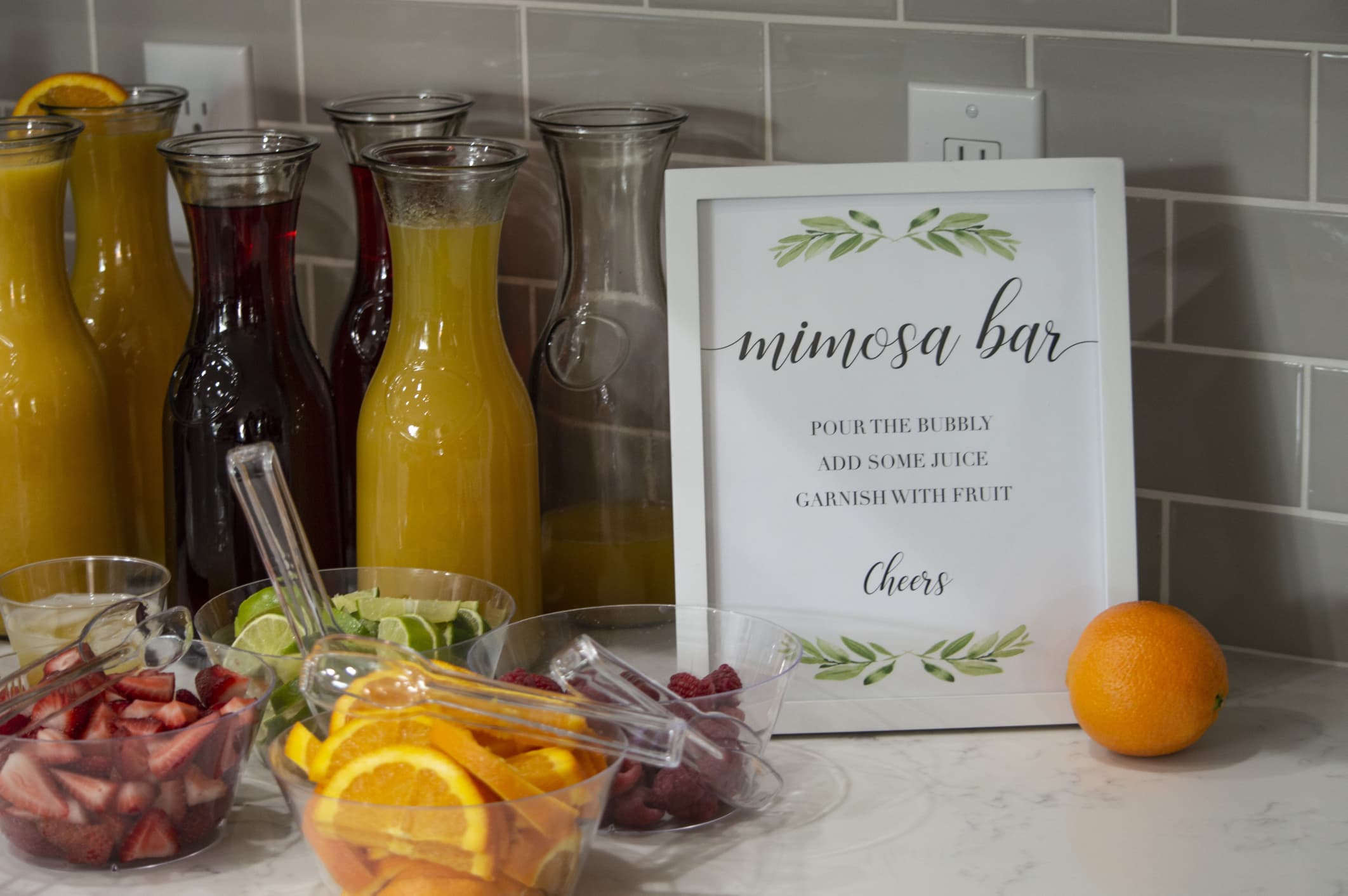 A mimosa bar complete with freshly sliced oranges, strawberries, limes, and raspberries.