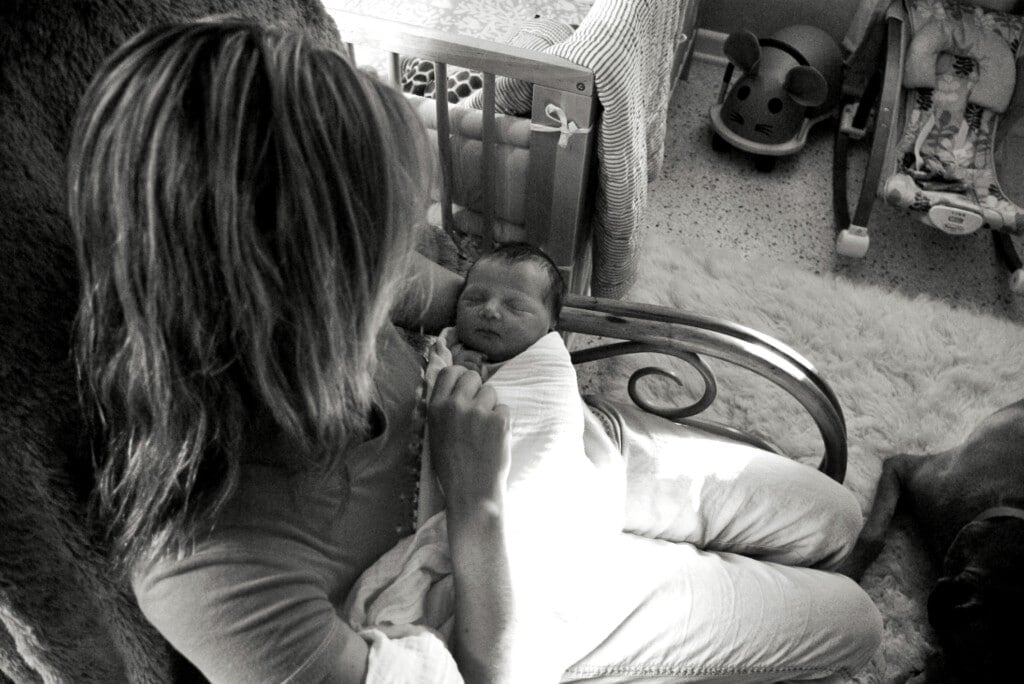 Woman rocking new baby in nursery.