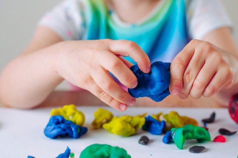 Close up of kids hands molding colorful child's play clay. Learning educational activities for children at home or in kindergarten.