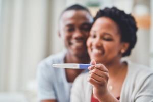 Cropped shot of a young couple smiling as she holds up a positive pregnancy test up