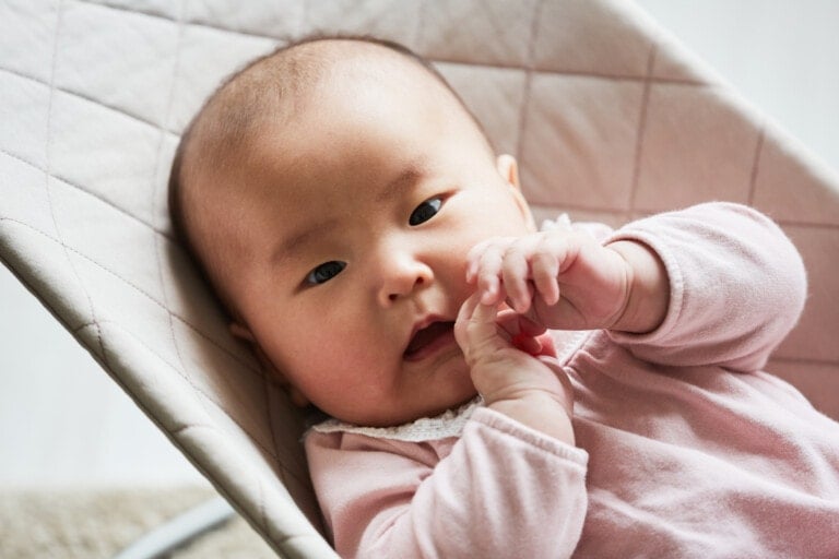 Close-up of Asian cute baby girl looking at camera while lying down on the bed