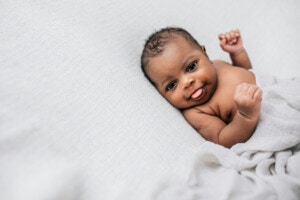Beautiful African-American newborn little boy just a few weeks old swaddled in a cream colored soft blanket with copy space