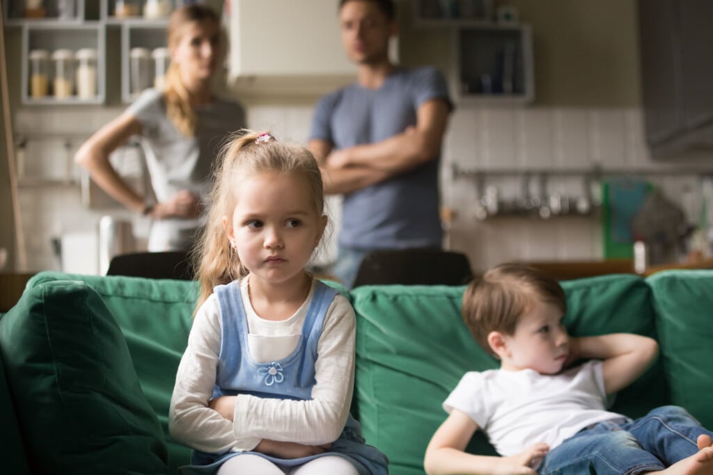 Frustrated kid girl feels upset, offended or bored ignoring avoiding worried parents and brother, little sad sister not talking to child boy after fight sulking sitting on couch, siblings rivalry