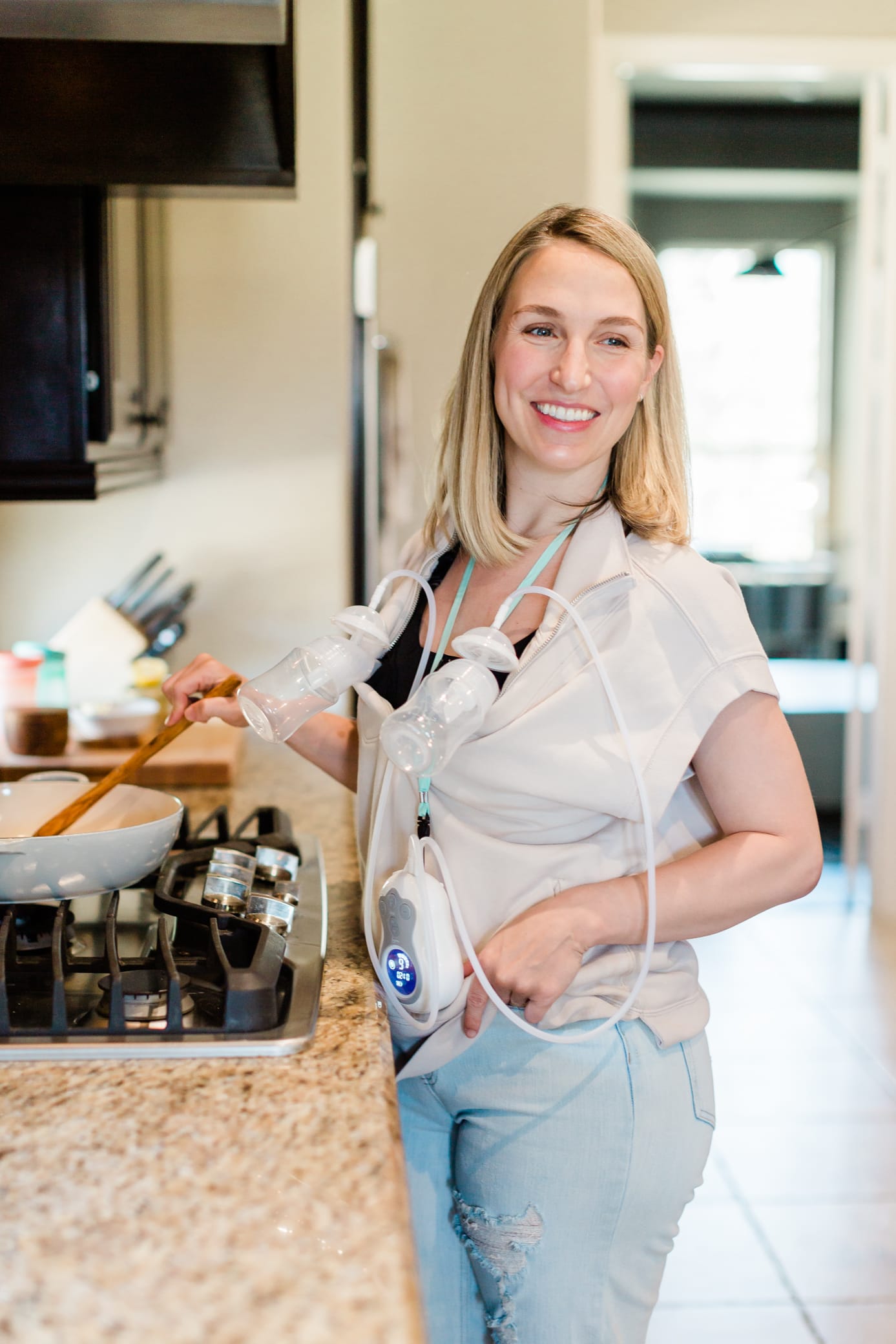 Mom cooking dinner and pumping with her Motif Duo breast pump.