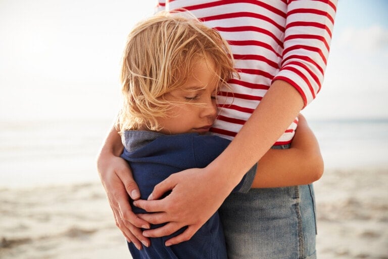 Close Up Of Mother Hugging Son On Summer Beach Vacation