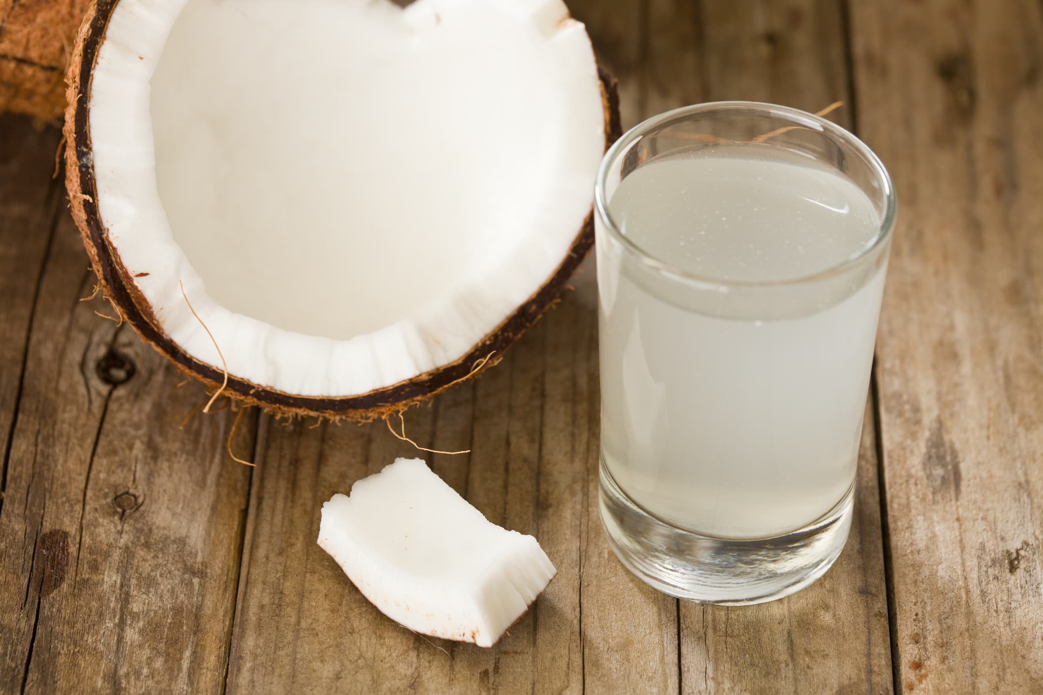 "A high angle close up of half a coconut and a tumbler full of coconut water, coconut water is said to be rich in potassium and antioxidants."