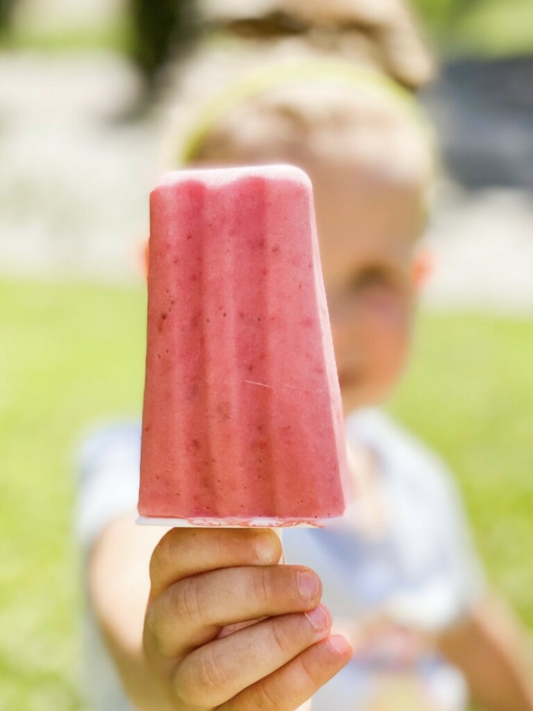 Little girl holding up a popsicle.